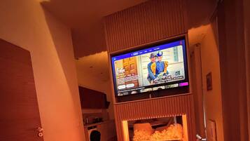 A hotel room with a bed, a television mounted on a wooden panel, and a washing machine in the background.