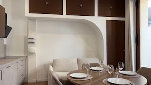 Uma área de refeições moderna com uma mesa redonda, cadeiras e um módulo de cozinha embutido com armários.
