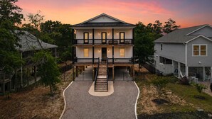 Ein zweistöckiges Haus mit Veranda, Auffahrt und umzäunter Garten.