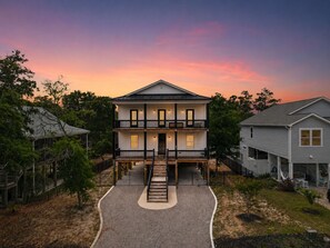 Ein zweistöckiges Haus mit Veranda, Auffahrt und umzäunter Garten.