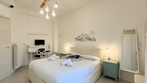 Ein Schlafzimmer mit einem Bett, Nachttischen, einem Schreibtisch mit Computer und einer Heizung, sowie einer Wanddekoration.
