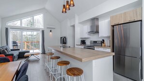 Una cucina moderna con isola centrale, sgabelli da bar e frigorifero in acciaio inossidabile.