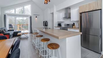 Una cocina moderna con una isla central, taburetes de bar y un refrigerador de acero inoxidable.