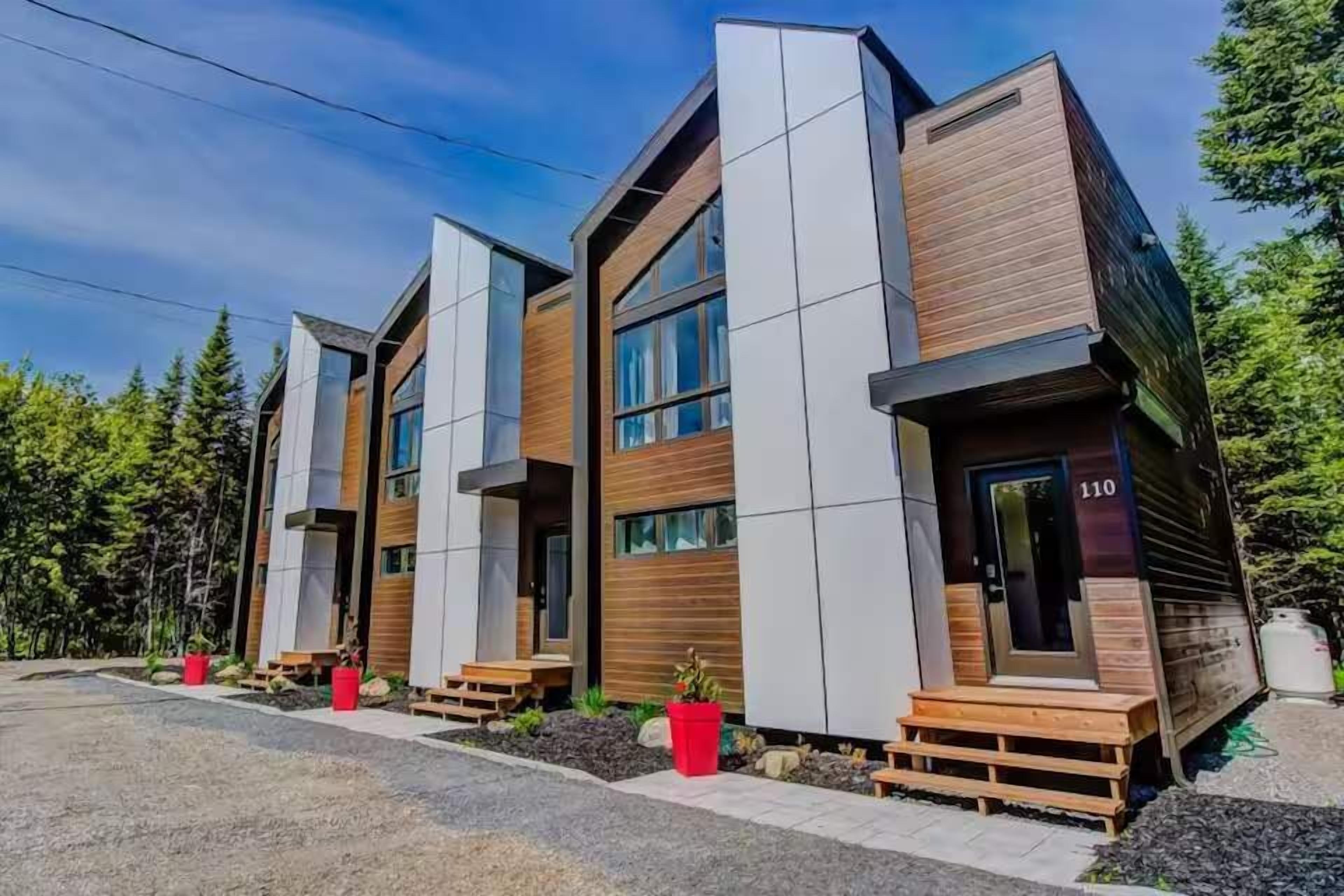 Un edificio moderno de varios pisos con amplios ventanales y fachada combinada de madera y concreto.