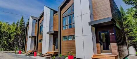 Un edificio moderno de varios pisos con amplios ventanales y fachada combinada de madera y concreto.