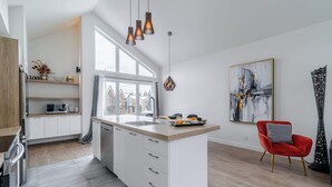 Una cucina moderna con mobili bianchi, una grande finestra e una sedia rossa.
