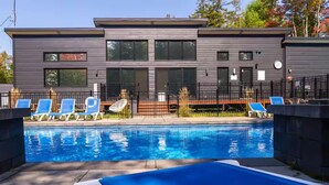 Un edificio moderno con piscina, sedie a sdraio e recinzione.