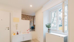 A room with a white radiator, a window with a view, a white cabinet, and a door. - Apartment for rent at Rua de Santo Estevão 25, Santa Maria Maior, Lisbon. (Lisboa)