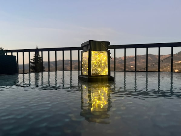 A lantern on a reflective surface with a mountainous view in the background.