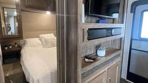 A bedroom with a bed, a TV, and a small cabinet. - Family Camper in Isabela (Isabela)