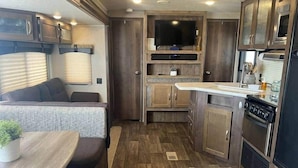 A compact RV kitchen with a stove, microwave, and a small countertop. - Family Camper in Isabela (Isabela)