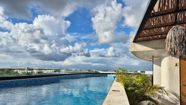 Una piscina con cielo azul despejado y nubes al fondo.