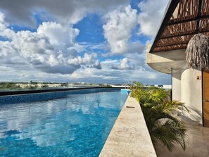 En swimmingpool med blå himmel og skyer i baggrunden.
