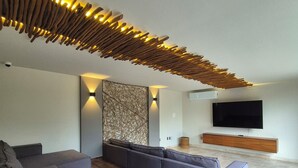 Una sala de estar moderna con un sofá seccional, un televisor de pantalla plana y una lámpara de techo original.