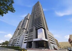 A high-rise building with a modern architectural design, featuring multiple floors and a prominent entrance. - Luxe JVC Studio with Skyline Views, Pool and Gym (Dubai)