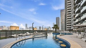 A rooftop pool with a circular design, surrounded by lounge chairs and a cityscape view.