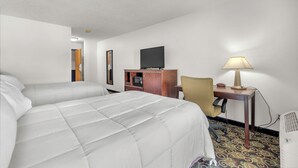 Une chambre d’hôtel avec deux lits, un bureau avec une lampe, une télévision et une armoire.