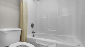 Une salle de bain équipée de toilettes, d’une baignoire et d’un rideau de douche.