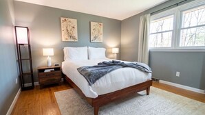 A bedroom with a bed, nightstands, lamps, and artwork on the walls. - Work + Relax + Play | 3BR Home w/ Ping Pong Table (Liverpool)