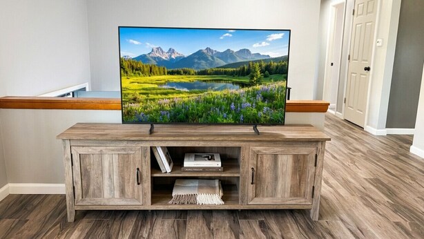 A wooden entertainment center with a flat-screen TV, two cabinets, and a shelf with books and a blanket. - Work + Relax + Play | 3BR Home w/ Ping Pong Table (Liverpool)
