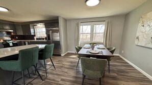 A modern kitchen with a bar area, dining table, and chairs. - Work + Relax + Play | 3BR Home w/ Ping Pong Table (Liverpool)