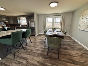 A modern kitchen with a bar area, dining table, and chairs. - Work + Relax + Play | 3BR Home w/ Ping Pong Table (Liverpool)