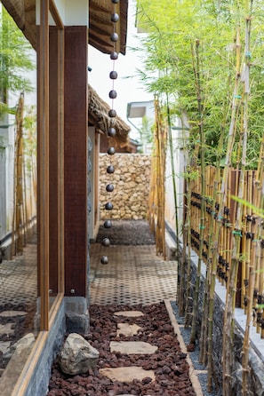 A pathway lined with bamboo and a stone wall, leading to a traditional building with a thatched roof. - Mizu Homes (Lembongan Island)