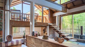 A wooden reception desk with a statue, a staircase, and large windows overlooking a natural landscape. - Mizu Homes (Lembongan Island)