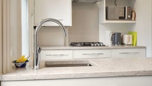 A kitchen with a stainless steel sink, white cabinets, a gas stove, and a microwave.