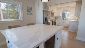Een moderne keuken met witte kasten, een groot eiland en uitzicht op de omgeving.
