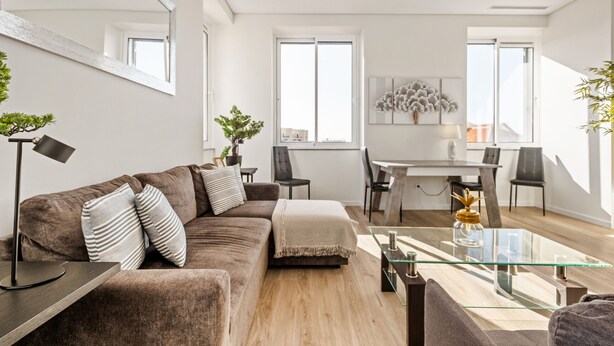 A modern living room with a glass coffee table, a brown sofa, and a dining area with a white table and chairs. - Sé Cathedral Rooftop, a Home in Madeira (Funchal)