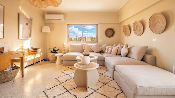 A modern living room with a sofa set, a coffee table, a floor lamp, and a large window with a city view. - Majorelle Luxury Retreat Fully Equiped (Marrakech)