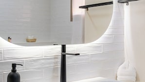 A bathroom with a white bathtub, a round mirror, and a black faucet. - Majorelle Luxury Retreat Fully Equiped (Marrakech)
