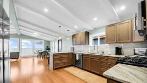 A modern kitchen with wooden cabinets, a marble countertop, and a view to the outside. - Panoramic Water Views (Lexington)