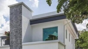 Une maison moderne à deux étages, dotée d’une façade en pierre, d’une grande fenêtre et d’un garage.