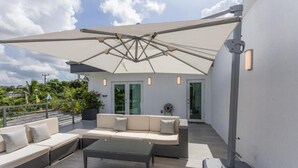 Une terrasse sur le toit, aménagée avec du mobilier d’extérieur, un grand parasol, et un bâtiment moderne en arrière-plan.