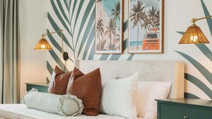 A neatly made bed with pillows, a green nightstand, and two wall-mounted lamps. - Villa De Le Mar - Pool, Movie Theater (Jacksonville Beach)