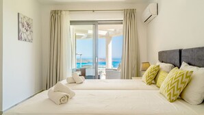 Ein Hotelzimmer mit Bett, einem Balkon mit Meerblick und einer Klimaanlage.