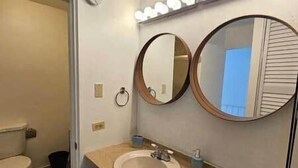 Ein Badezimmer mit Toilette, Waschbecken und zwei runden Spiegeln.