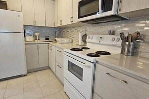 A kitchen with white cabinets, a stove, a microwave, and a sink. - W4-Beach Villa in Dorado (Dorado)