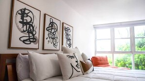 A bedroom with a bed, pillows, and three framed abstract art pieces on the wall. - Prime Location in Condado Puerto Rico (San Juan)