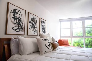 A bedroom with a bed, pillows, and three framed abstract art pieces on the wall. - Prime Location in Condado Puerto Rico (San Juan)