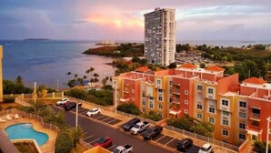 A coastal residential area with a high-rise building, a swimming pool, and parked cars. - P1207-Oceanview Apartment- Peñamar (Fajardo)