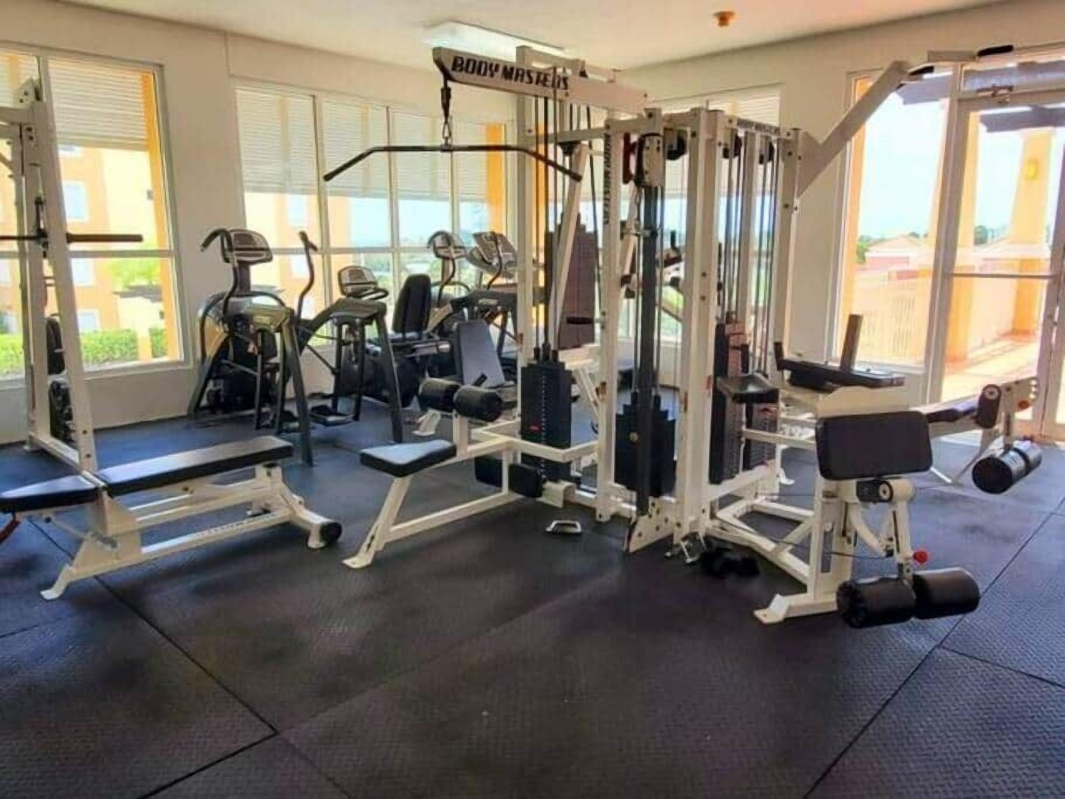 Een fitnessruimte met diverse trainingsapparaten, waaronder krachtapparaten en losse gewichten.