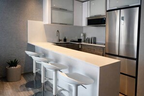 Eine moderne Küche mit Kochinsel, Edelstahlgeräten und Barhocker.