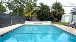 Une piscine rectangulaire dont le bord est recouvert de carrelage, entourée d’une terrasse en béton.