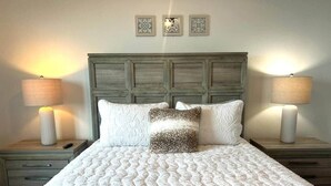 Un letto con copriletto bianco, due comodini con lampade e una testiera in legno.