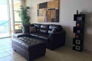 A living room with a sectional sofa, a coffee table, a wall-mounted shelf, and a potted plant. - P1508-Comfortable apartment in Fajardo (Fajardo)