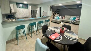 Una cocina moderna con barra, una mesa de comedor con sillas y una sala de estar con sofá.
