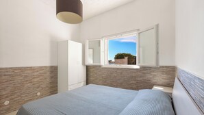 Ein Schlafzimmer mit Bett, Kleiderschrank, Fenster mit Aussicht und einer Deckenleuchte.